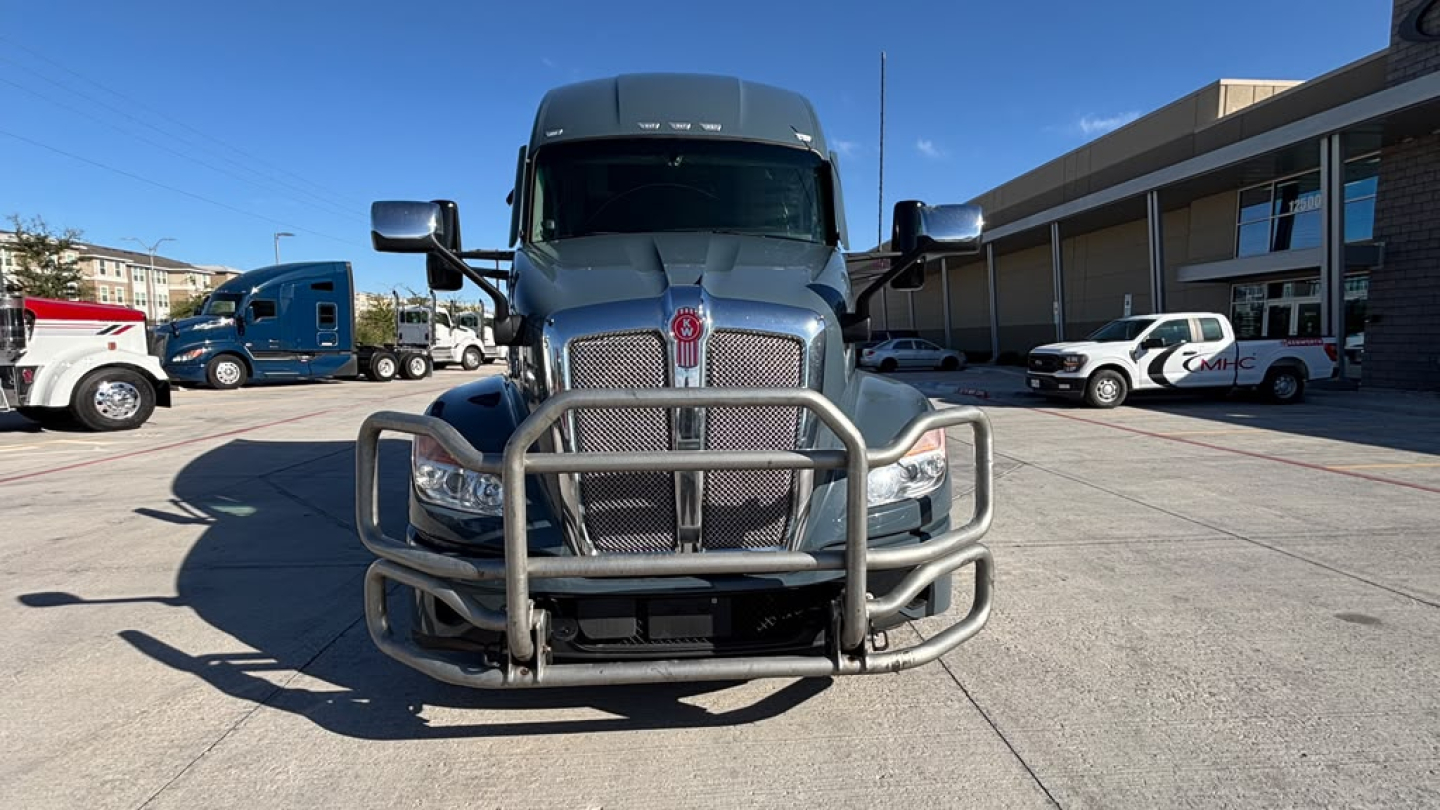 Kenworth T680 front view showing heavy-duty grille guard and bumper, chrome grille, large hood, front cameras, and bold Kenworth emblem.