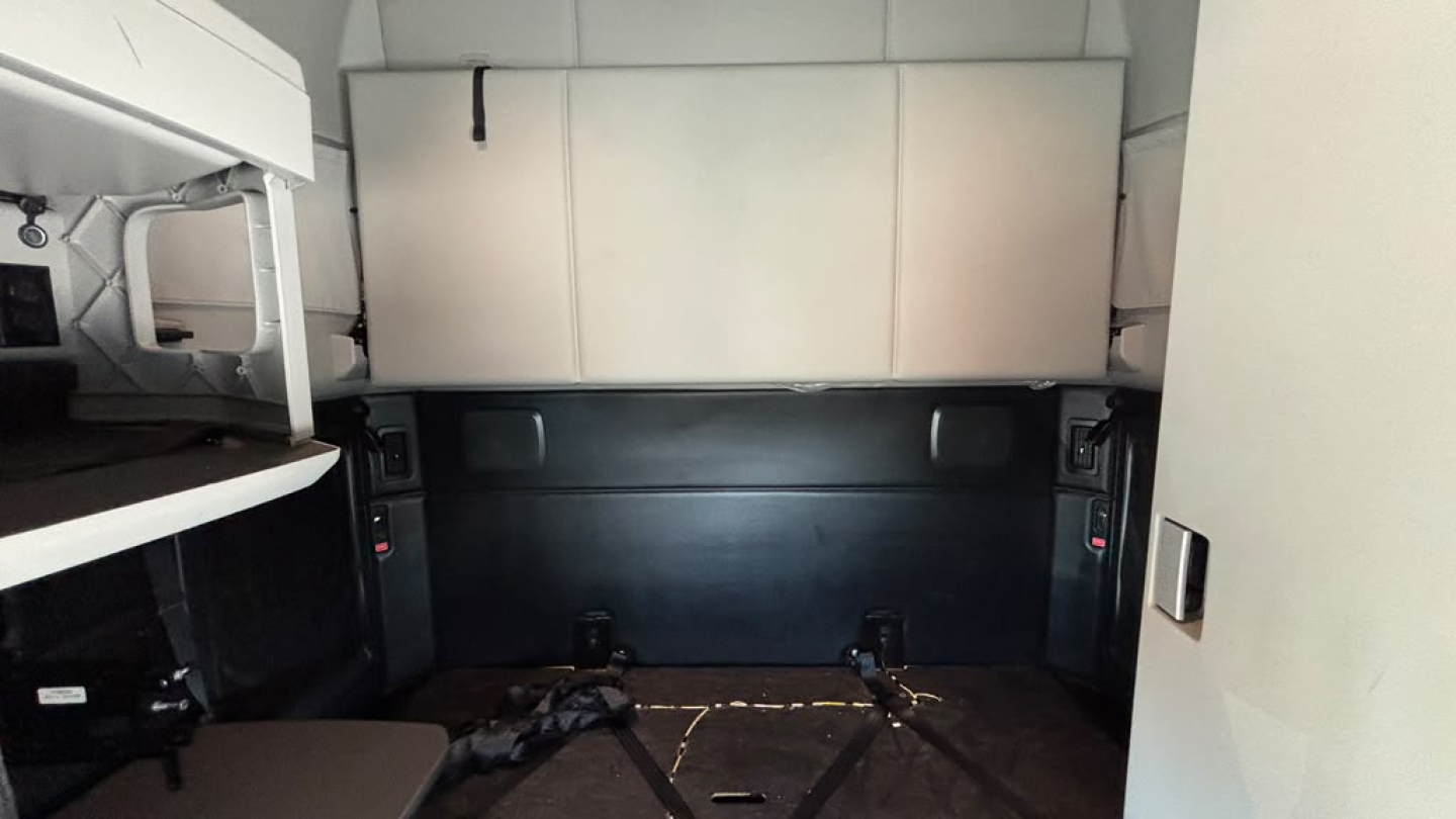 Kenworth T680 sleeper cab interior cargo area showing storage cabinets and side walls.