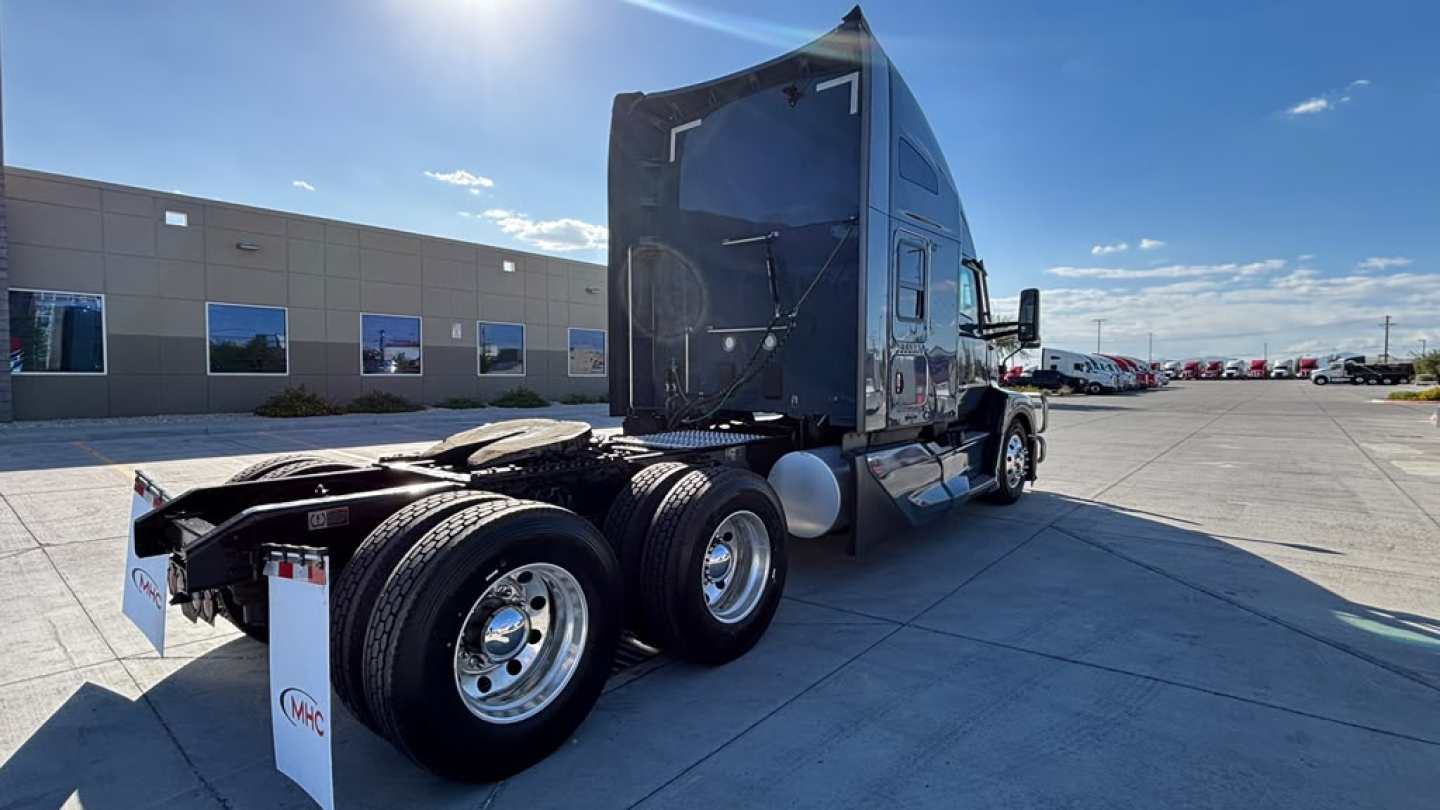 Kenworth T680 truck chassis rear view showing dual rear axles, fuel tanks, and sleeper cab. Visible stickers include VIN and stock information on the side.