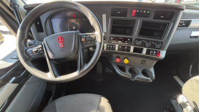 Kenworth T680 interior dashboard view with steering wheel, gauge cluster, and center console showing controls and cup holders.