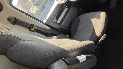 Kenworth T680 truck interior seat and door area visible from side cabin view with fabric seat, seatbelt buckle, and window frame.
