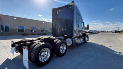 Kenworth T680 truck chassis rear view showing dual rear axles, fuel tanks, and sleeper cab. Visible stickers include VIN and stock information on the side.