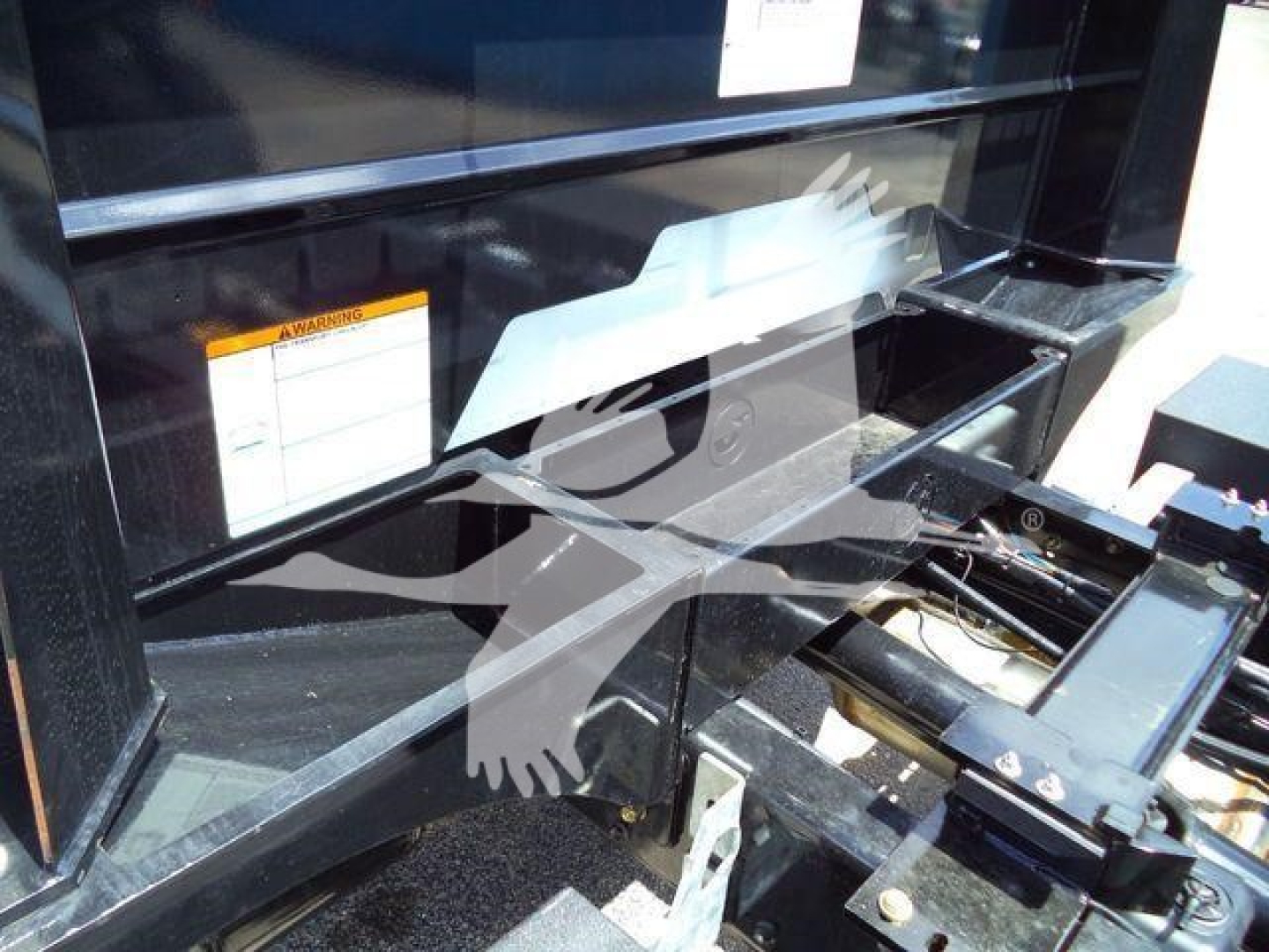 Truck chassis and hydraulic rollback mechanism showing metal framework and labels.