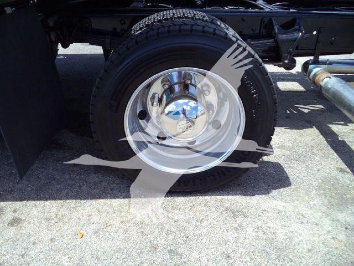 Truck wheel and part of chassis showing chrome hubcap and tire on Silverado rollback.