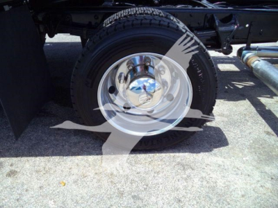 Truck wheel and part of chassis showing chrome hubcap and tire on Silverado rollback.