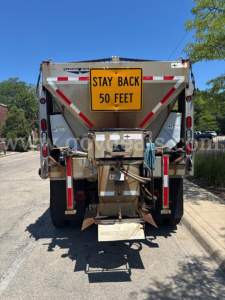 Rear view of a used 2009 International 7400 service/utility truck with a yellow 'STAY BACK 50 FEET' sign on the back, metal hitch, and warning cones.
