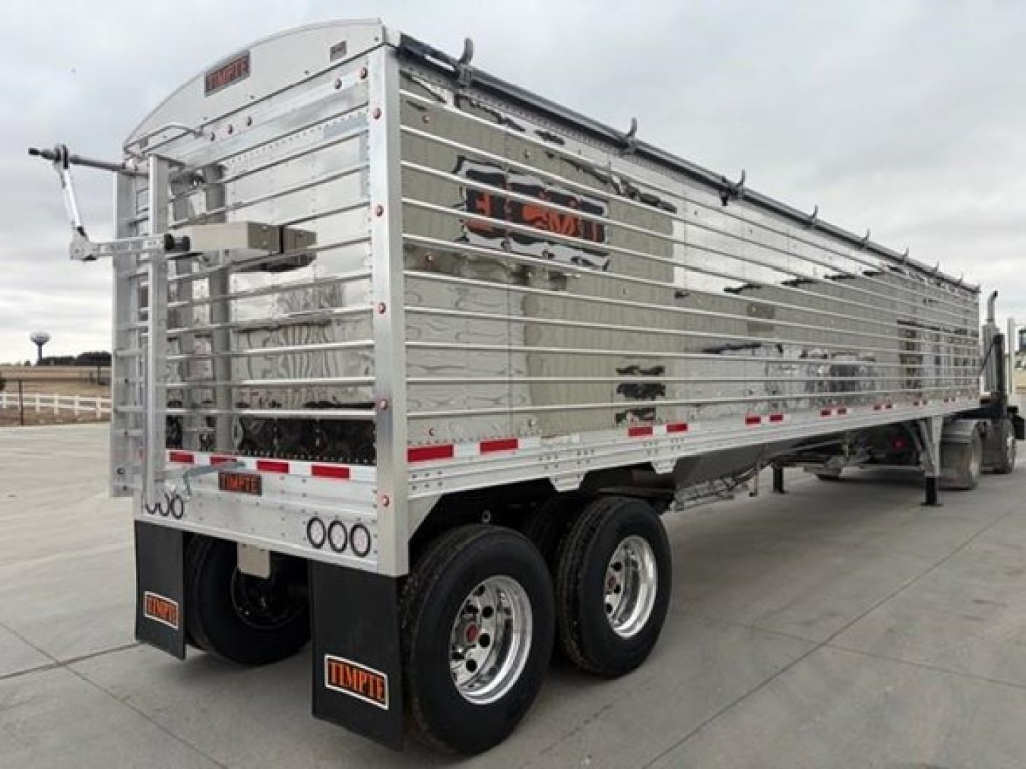 Trailer side view showing Timpte hopper trailer with reflective strips and dual rear wheels.