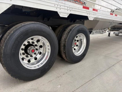 Trailer side showing dual rear axles with polished chrome wheels and black tires on a white Timpte Super Hopper trailer.