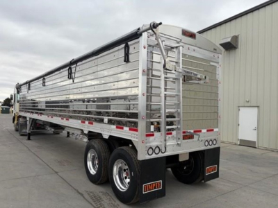 Timpte Super Hopper trailer rear three-quarter view showing aluminum side panels, tandem axles, and rear gate with latching mechanism.