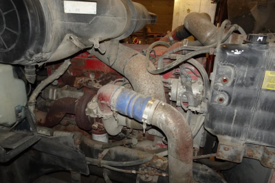 Engine bay of a 2005 International 9400 showing intake pipe, turbocharger, hoses, and air filter housing.