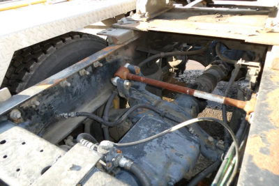 Truck engine bay showing hydraulic lines, hoses, and engine components under the chassis of a 2005 International 9400 conventional daycab.