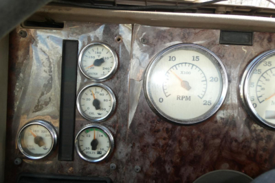 Dashboard cluster with multiple gauges in a brown textured panel; includes RPM gauge and smaller oil pressure/voltage gauges.