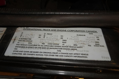 Label plate on International truck showing gross vehicle weight, front axle, rear axle, engine specs and tire information. Text includes CANADA International Truck and Engine Corporation plate with weights and tire data.