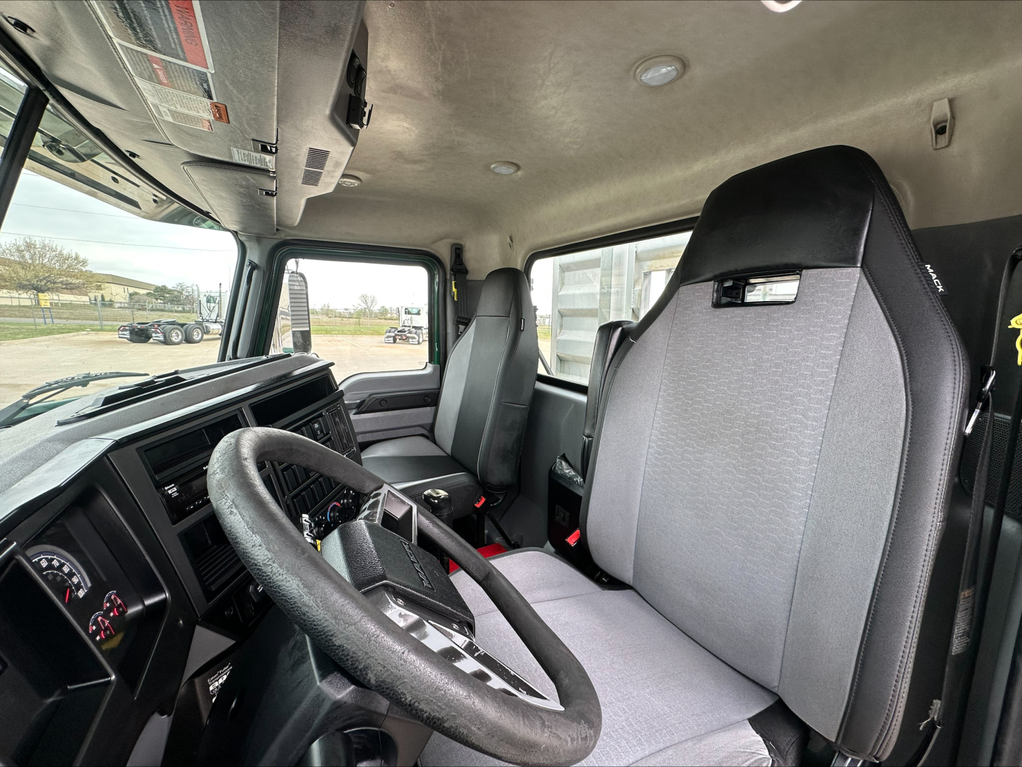 Cab interior of a 2020 Mack PI64T tractor showing steering wheel, driver seat, and dashboard with a wide windshield.