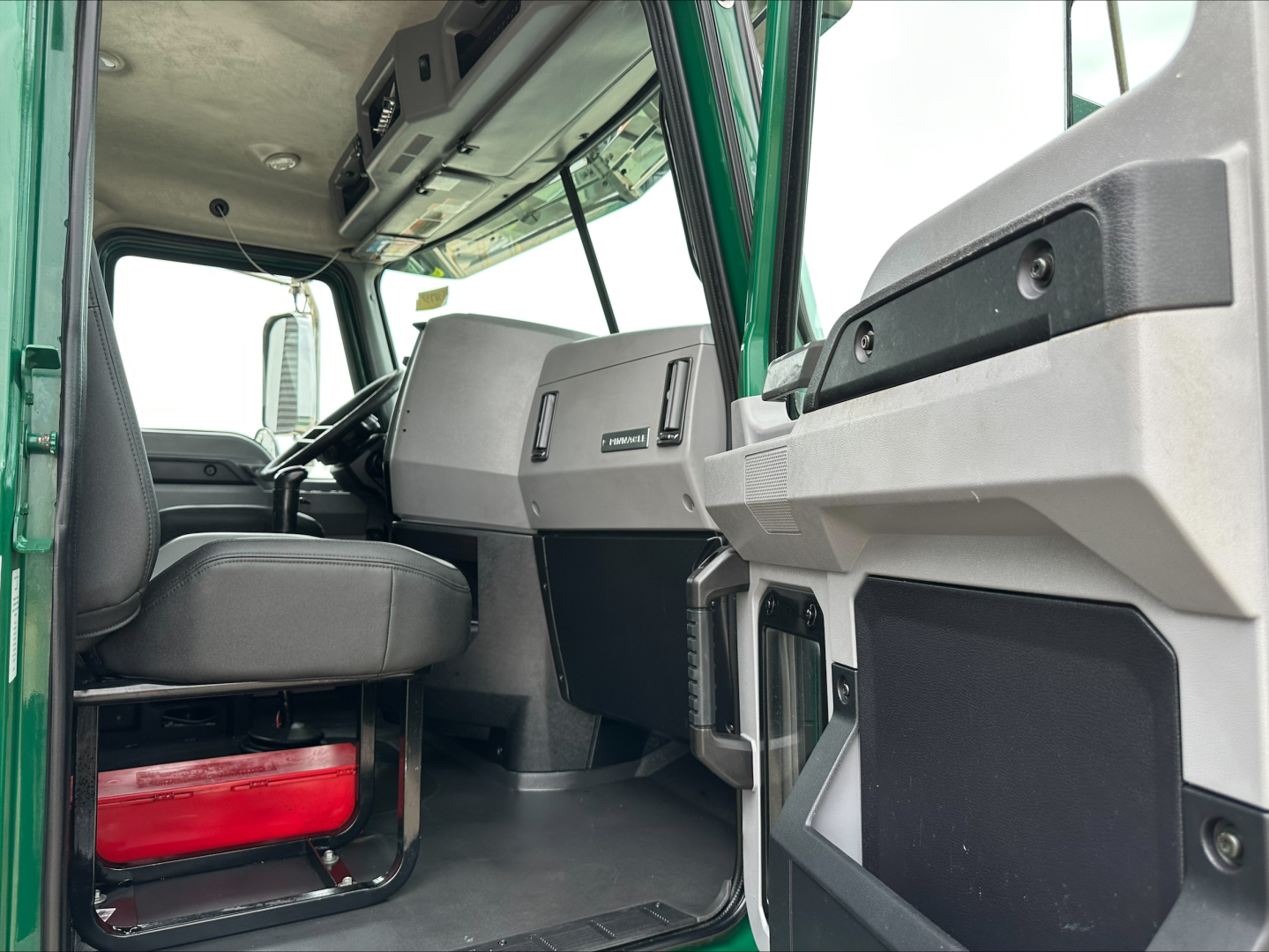 Cab interior of a 2020 Mack PI64T daycab showing driver seat, dashboard, and door panel with storage pockets.
