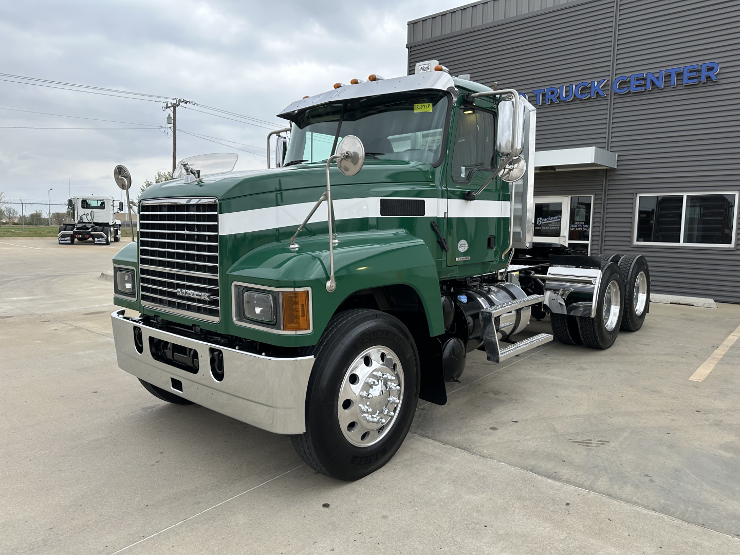 Mack PI64T conventional daycab truck front-left view showing green and white exterior and chrome bumper