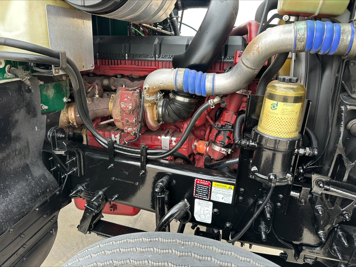Mack PI64T engine bay showing red diesel engine, blue silicone hoses, black metal frame, and yellow oil/ filter housing.