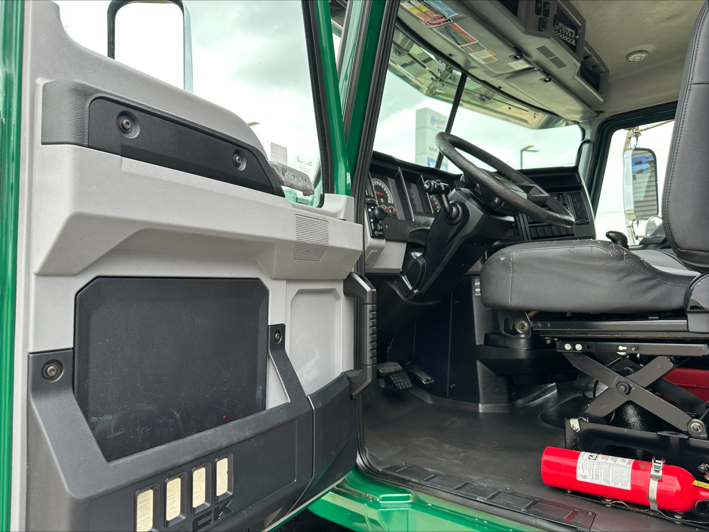 Truck cab interior with door panel and steering wheel; visible text includes none clearly legible.