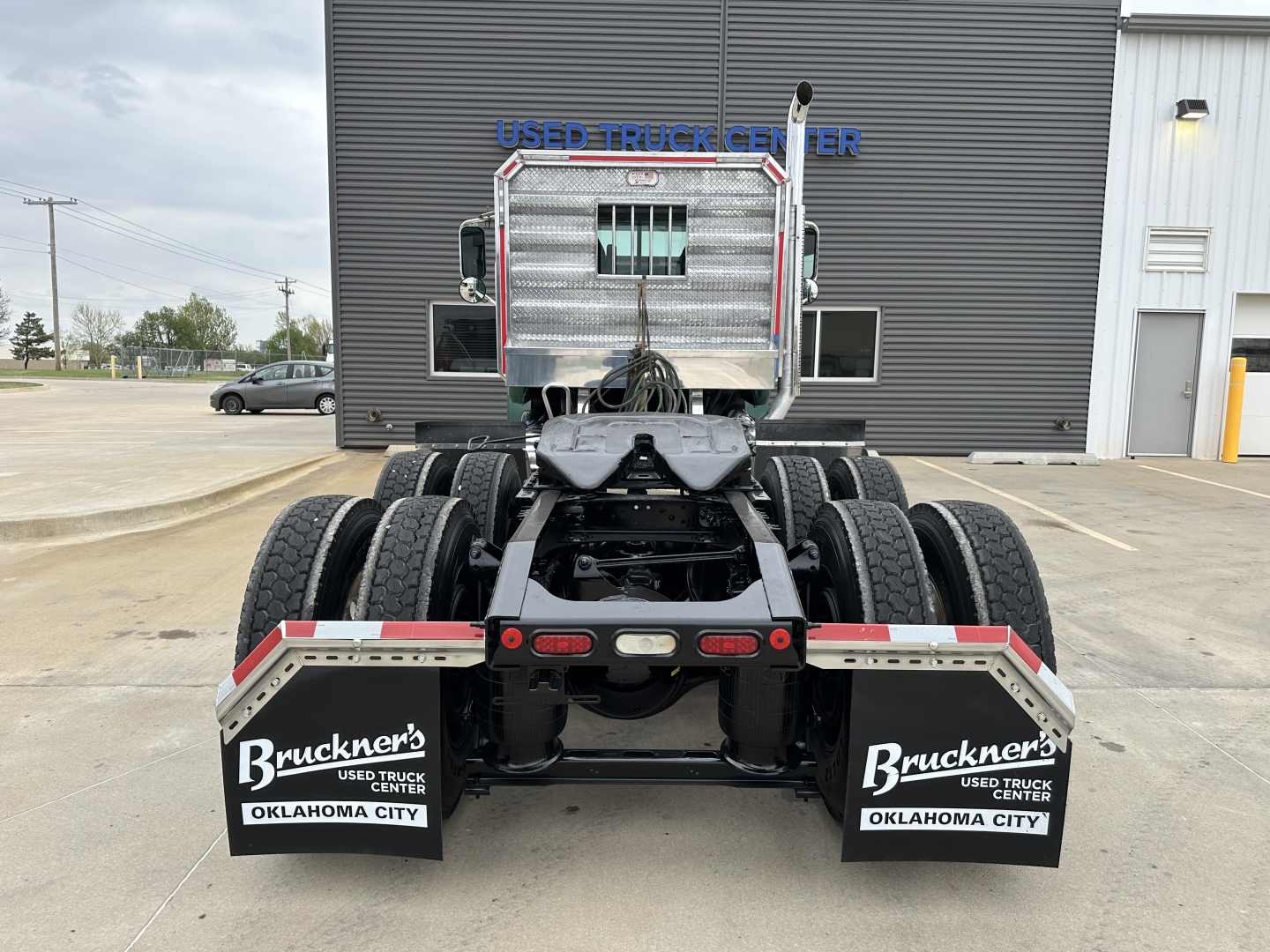 Rear view of 2020 Mack PI64T conventional daycab truck chassis showing dual rear axles, mud flaps with Bruckners Oklahoma City branding, and license plate mounts.