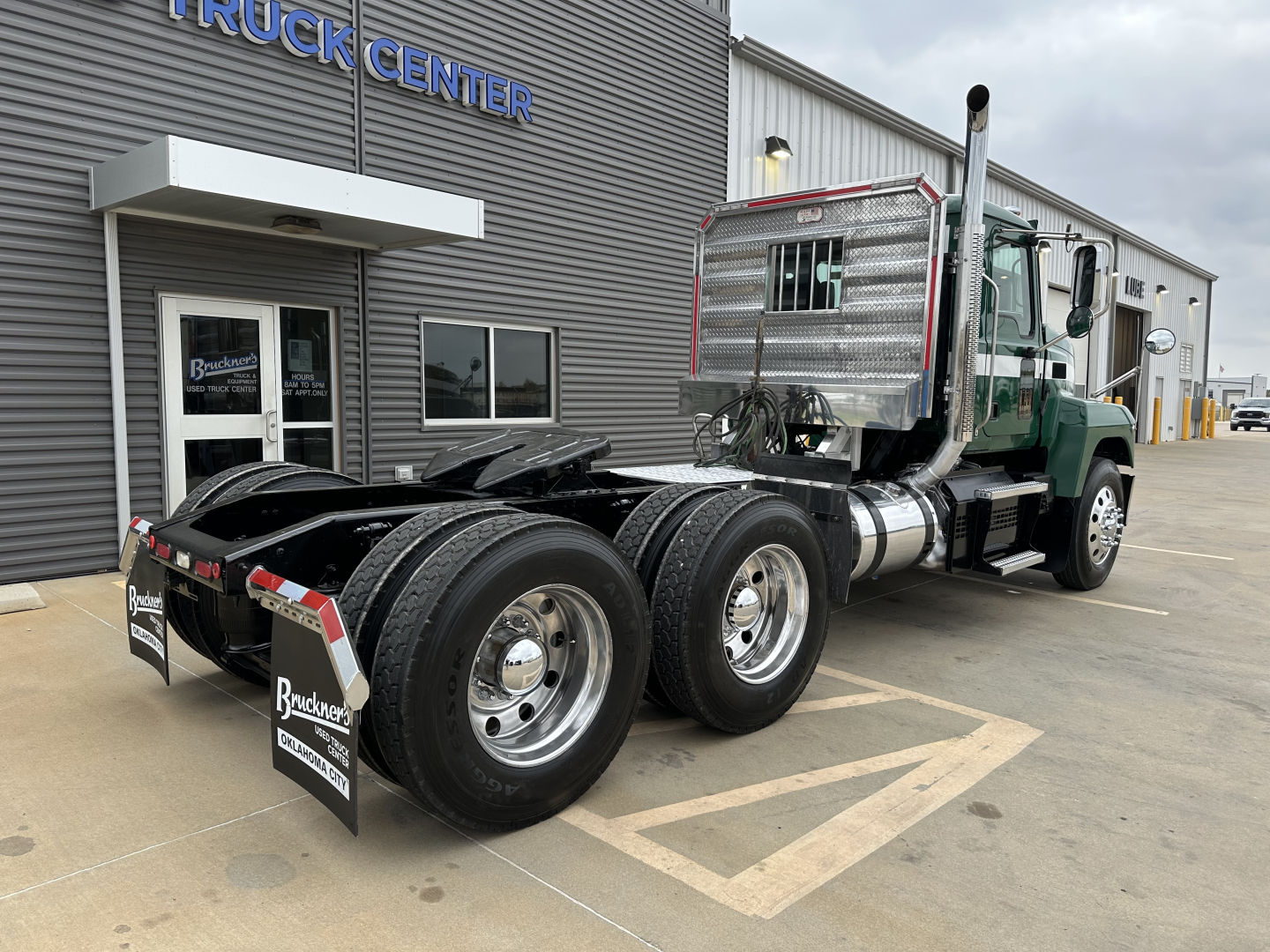 Mack PI64T truck tractor rear and cab view showing dual rear axles, aluminum fuel tanks, and chrome exhaust stacks with stainless sleeper cab area