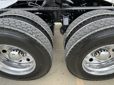 Dual rear truck wheels and suspension beneath a 2020 Mack PI64T showing twin rear tires with chrome rims and part of the chassis.