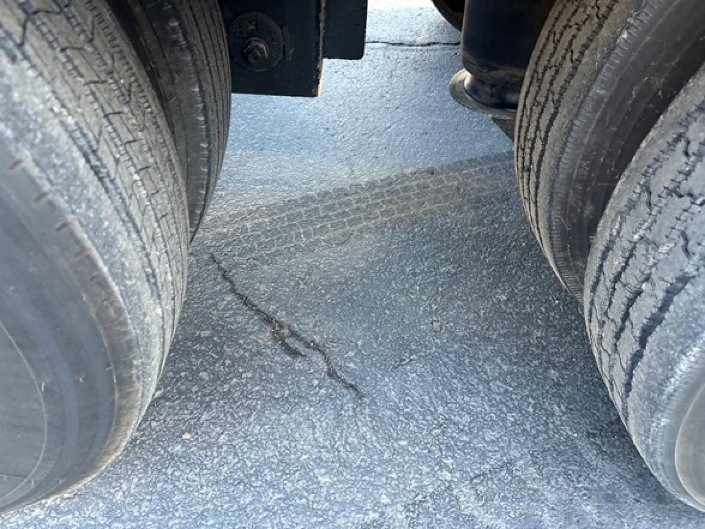 Trailer wheels and gap between tandem axles on a Load King 55-ton lowboy showing dual tires and road surface.