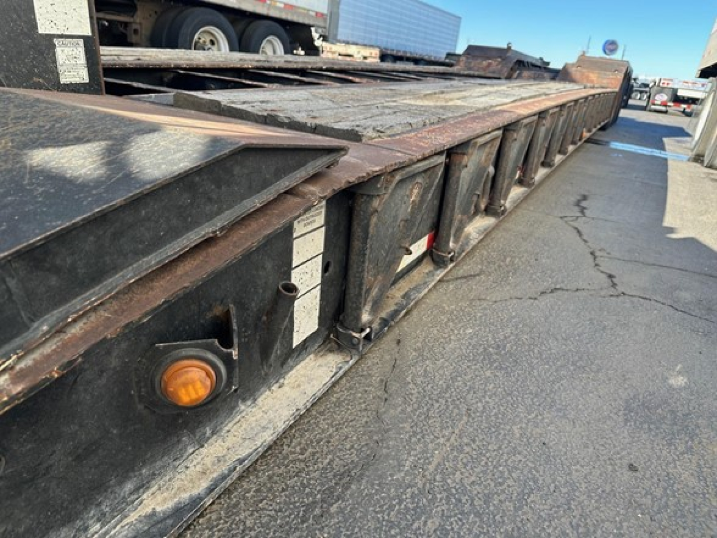 Load King 55 ton lowboy trailer side with deck and pins, showing orange side marker light and flatbed edge.