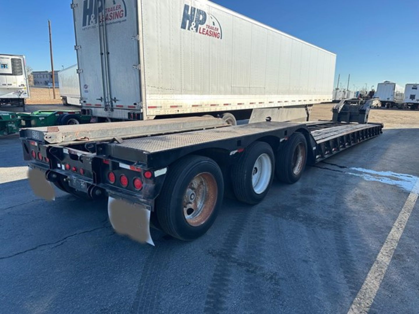 Load King 55 Ton lowboy trailer showing tandem rear axles and heavy-duty deck with auger wheel wells and rear lights.