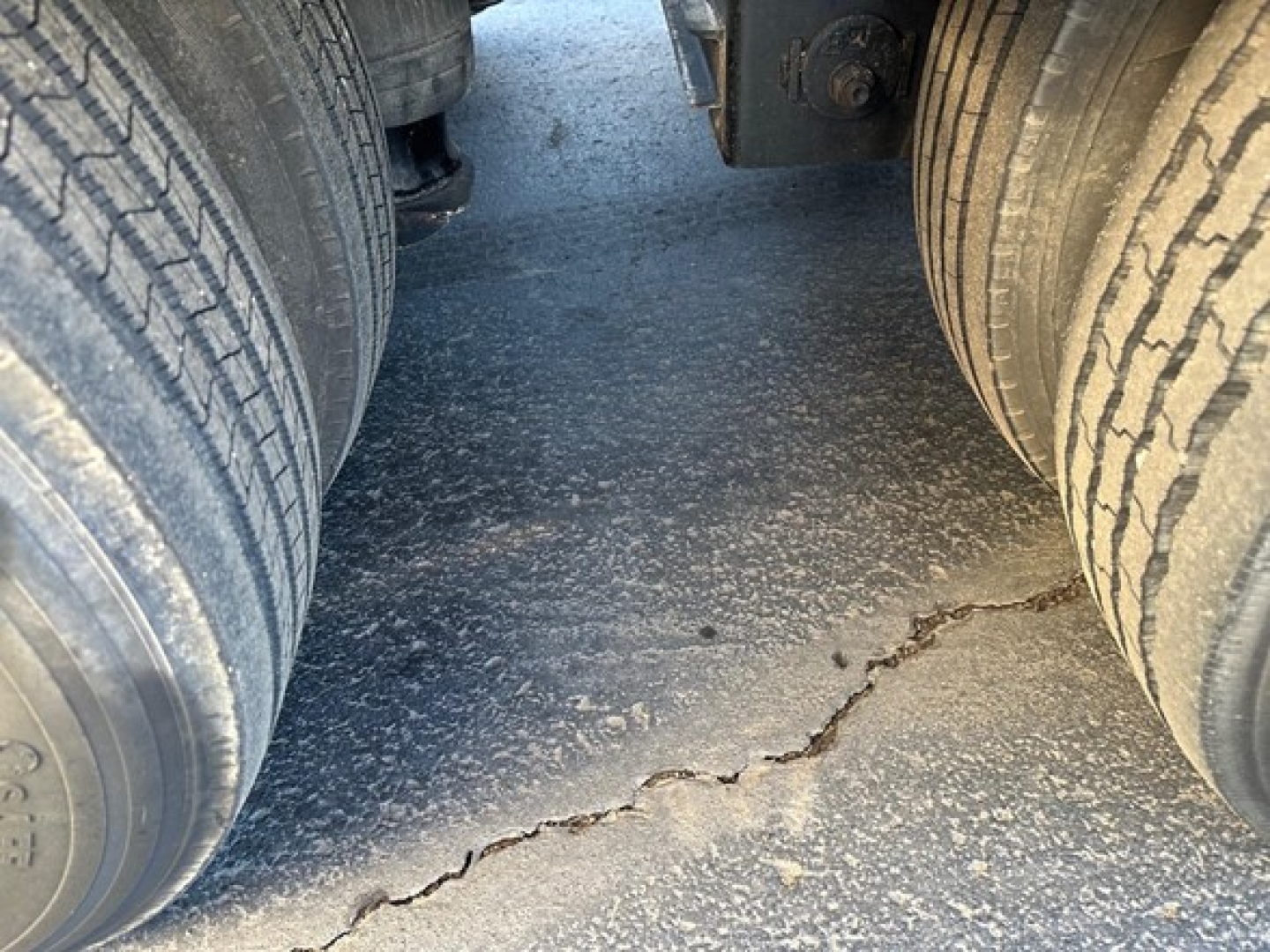 Load King 55 ton lowboy trailer view between dual rear tires showing cracked asphalt surface