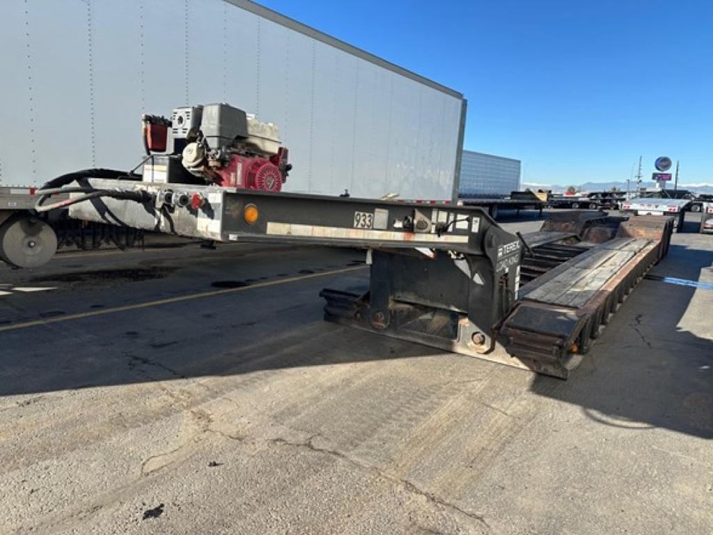 Load King 55 Ton Lowboy trailer showing hydraulic pump and long deck with dual axle configuration and brand tag.
