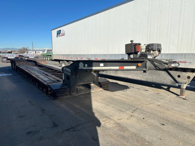 Load King 55 Ton lowboy trailer with long flatbed and gooseneck; side rails; hydraulic catwalk; utility boxes; white trailer in background.