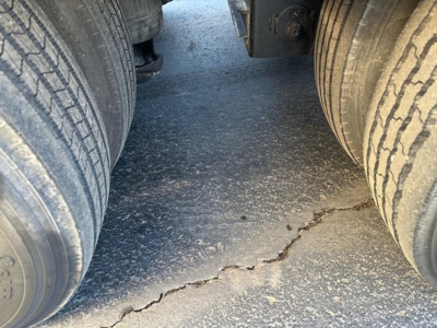 Load King 55 ton lowboy trailer view between dual rear tires showing cracked asphalt surface