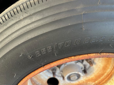 Trailer wheel/tire with visible tire size 255/70 R22.5 and rusted rim edge on a Load King 55 Ton lowboy trailer.