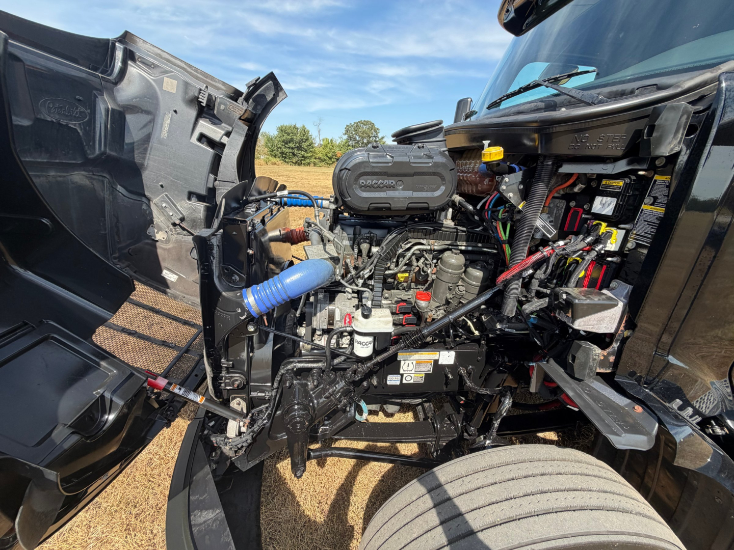 Peterbilt 579 engine bay showing 6-cylinder diesel engine with exposed components and air intake hose.