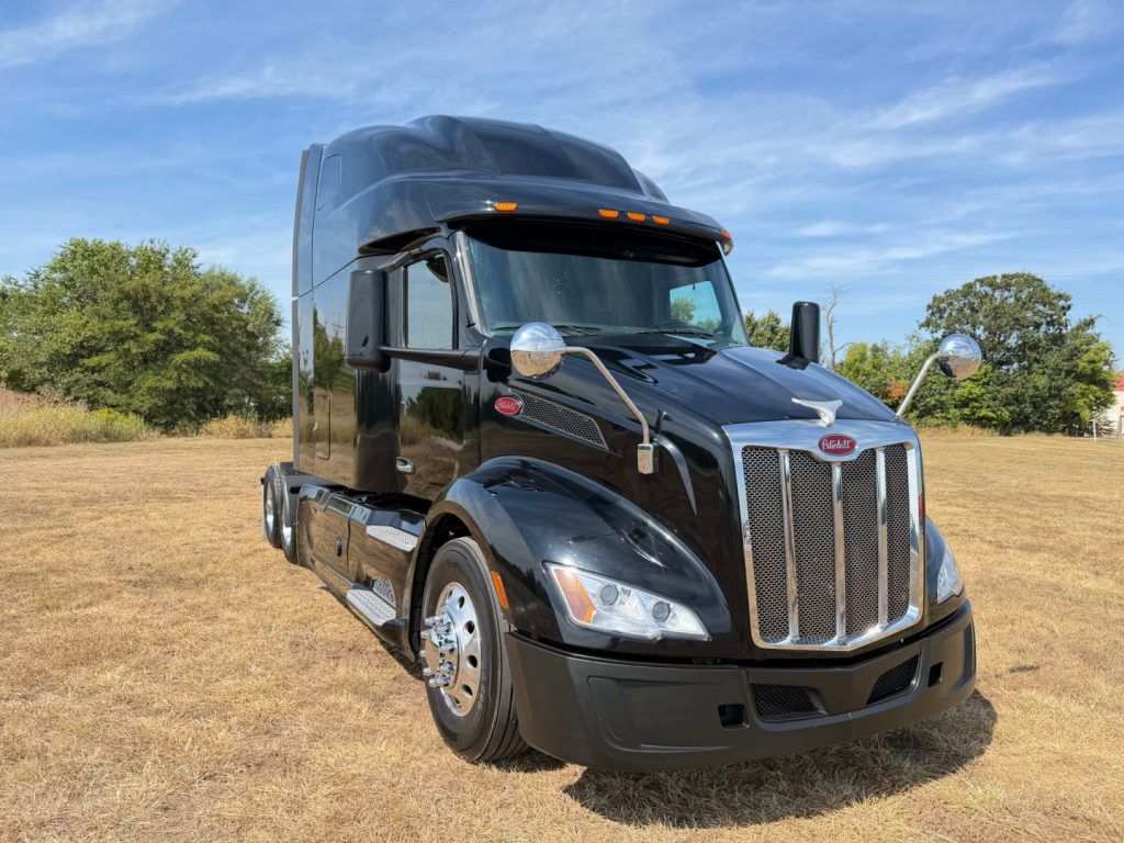 Peterbilt 579 truck in a field showing front grille and cab details with chrome mirrors and sleeper