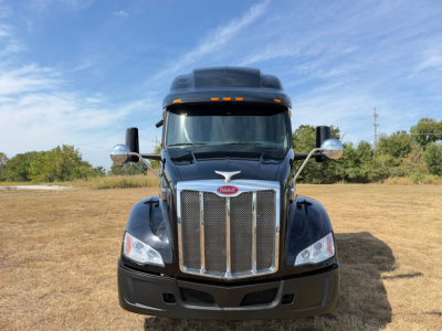 Peterbilt 579 truck front view showing chrome grille, headlights, and large side mirrors in an open field.