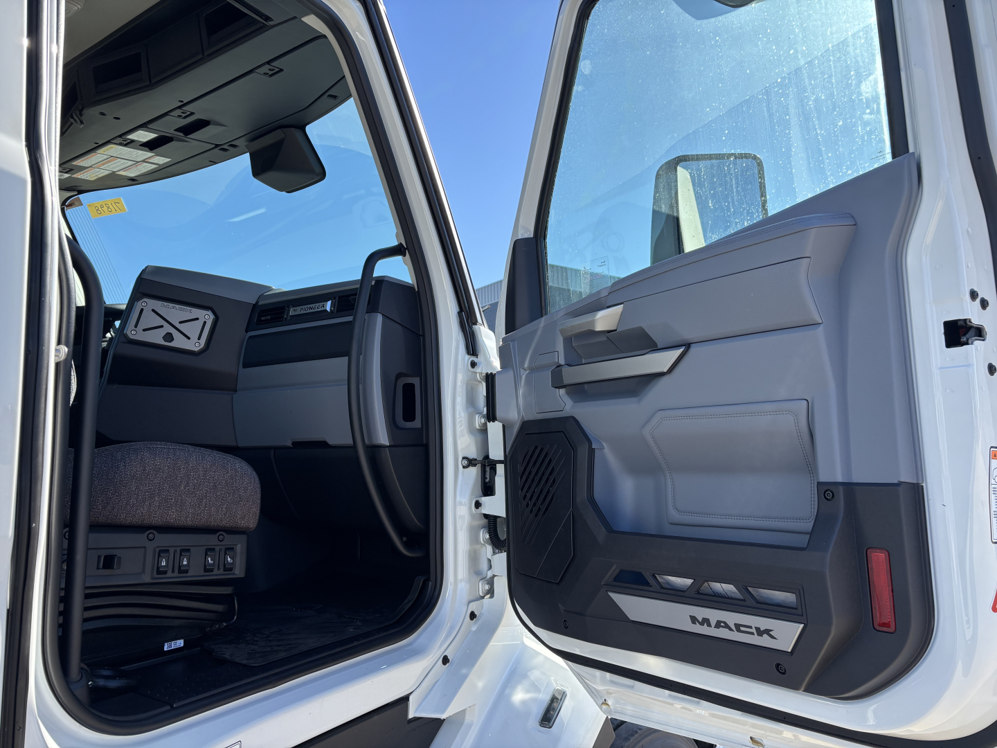 Mack PR64T truck cab interior and door sill showing open entry with steering wheel and dashboard visible.