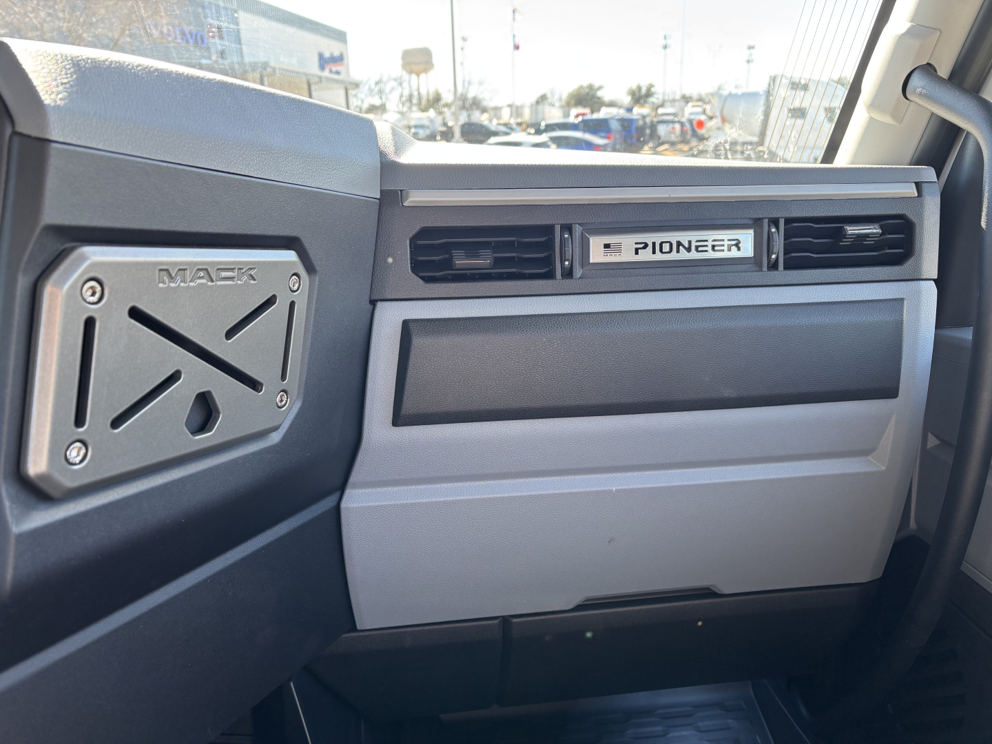 Dashboard and passenger-side interior of a 2027 Mack PR64T truck showing Mack badge on left and Pioneer emblem on dash near air vents.