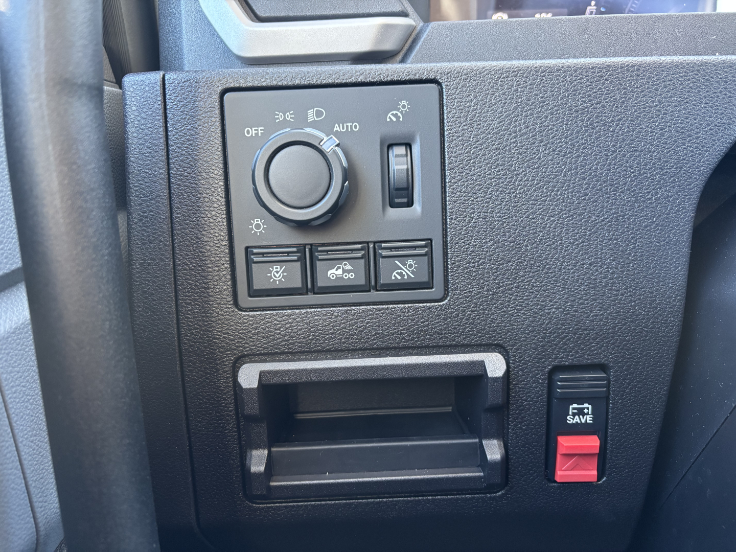 Mack PR64T interior dash panel showing climate control knob, switches, small storage slot, and red SAVE button.