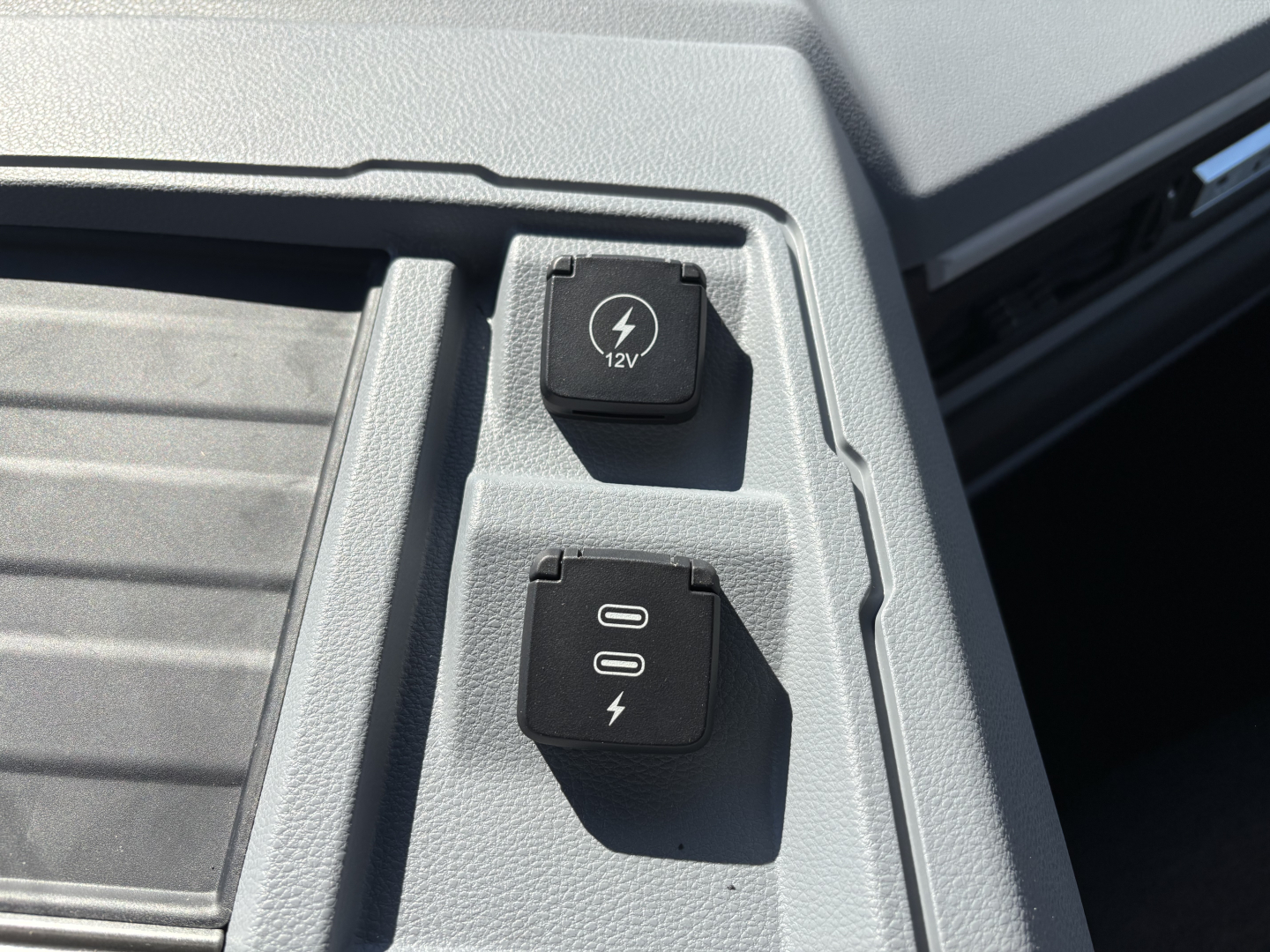 12V power outlet and USB/auxiliary power switch panel in Mack PR64T cab interior showing 12V socket and two-switch with USB-like icon.