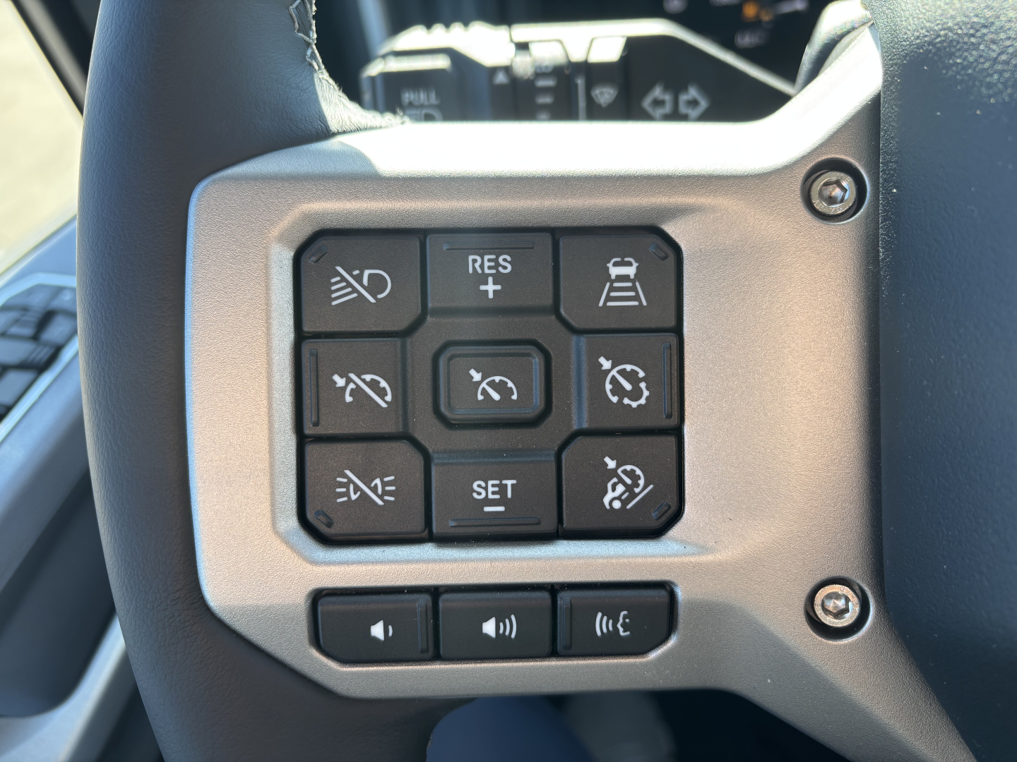 Truck steering wheel controls showing cruise control and multi-function buttons in a PR64T cab.