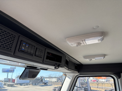 Cab interior roof console and overhead controls of a Mack PR64T truck cab, with a dome light, sun visor area, and dashboard electronics visible.