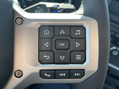 Steering wheel control cluster with many buttons on a Mack PR64T interior image showing home, back, OK, arrows, and media controls