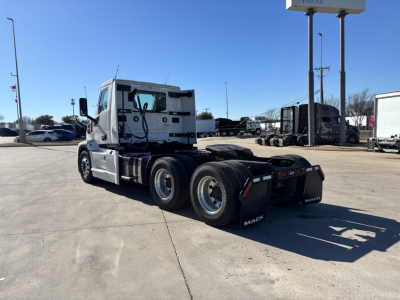 Mack PR64T tractor-trailer cab in a dealership lot, side view showing rear dual axles and fifth-wheel, with stock number 71899 in background