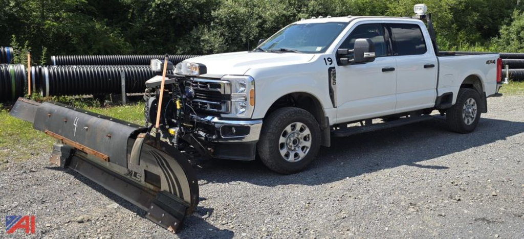 Ford F-350 Super Duty XLT Crew Cab with plow attached in a gravel lot.