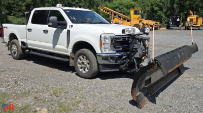 Ford F-350 Super Duty XLT Crew Cab pickup with plow attached, front view, white with grille guard, plow blade resting on ground.