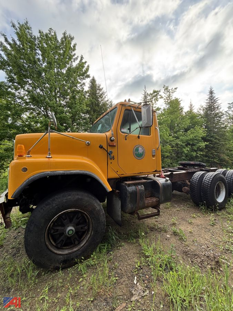 Orange 1992 International S2574 cab and chassis truck viewed from side, with front wheels, dual rear tires, and a green circular logo on the door.