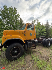 Orange 1992 International S2574 cab and chassis truck viewed from side, with front wheels, dual rear tires, and a green circular logo on the door.
