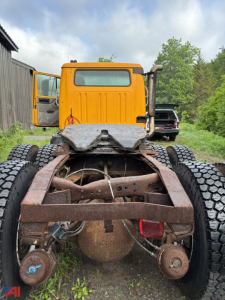 Cab and chassis showing rear view of a yellow International S2574 with exposed chassis and dual rear axles, no bed installed, with large off-road tires.
