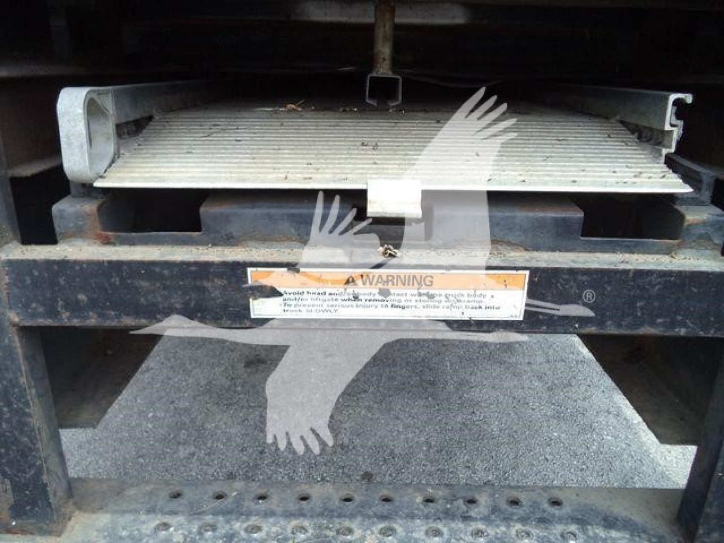 Truck refrigeration unit undercarriage with metal steps and warning label; visible text includes A WARNING on the label but is partially obscured.